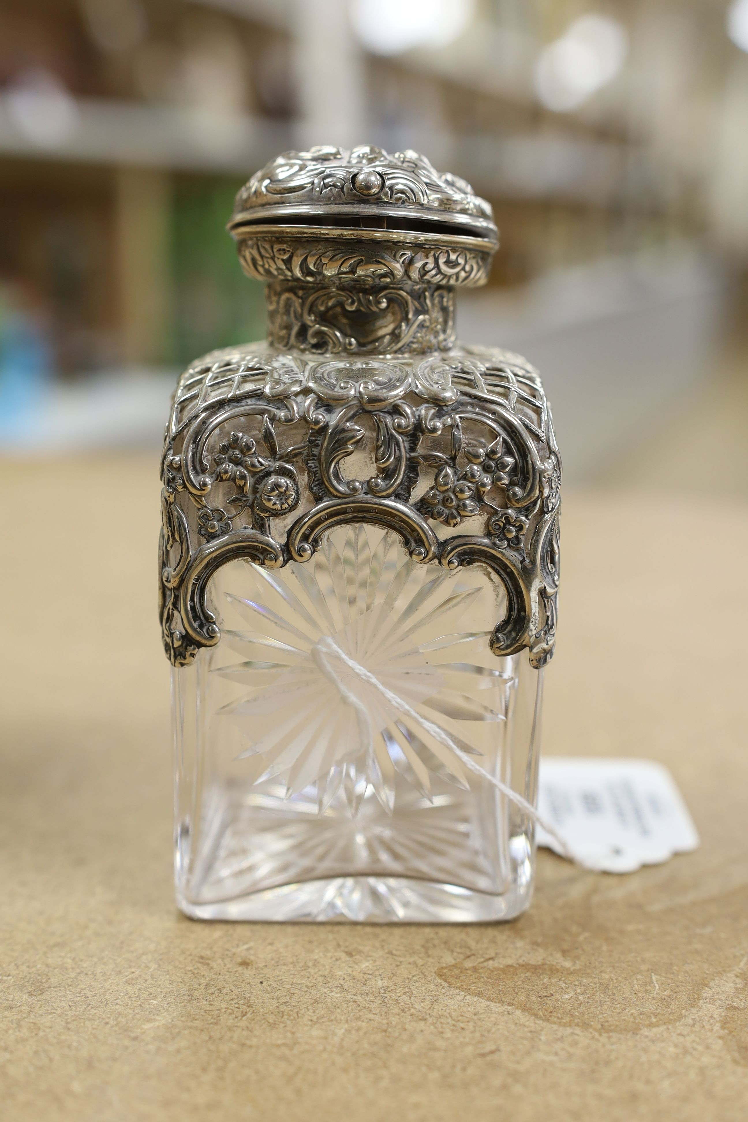 A pair of late Victorian repousse silver mounted cut glass scent bottles with stoppers, William Comyns, London, 1898, height 14.3cm.